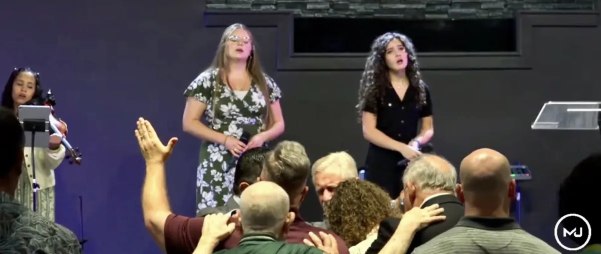 Church members gathered at the altar, laying hands on someone as they pray together