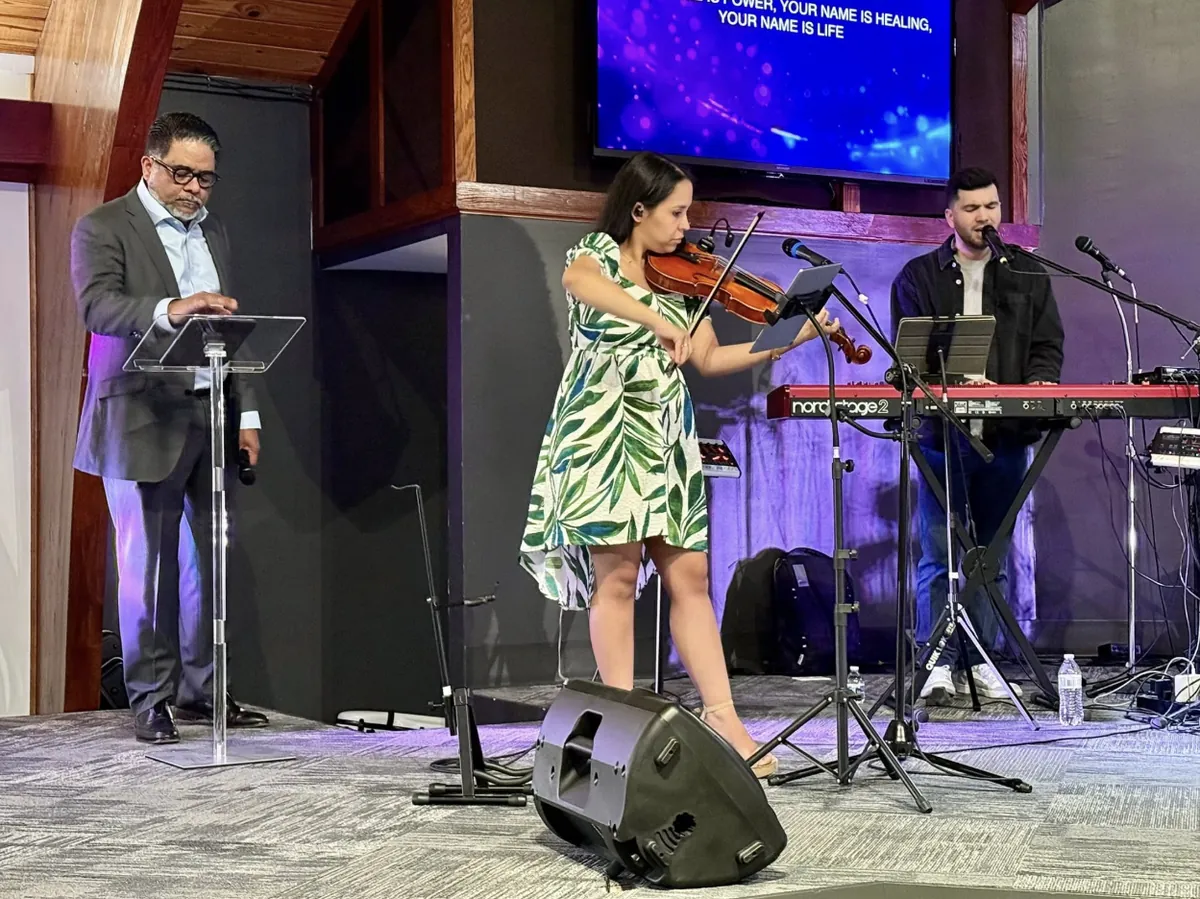 A violinist and a keyboardist leading worship on the sanctuary stage.